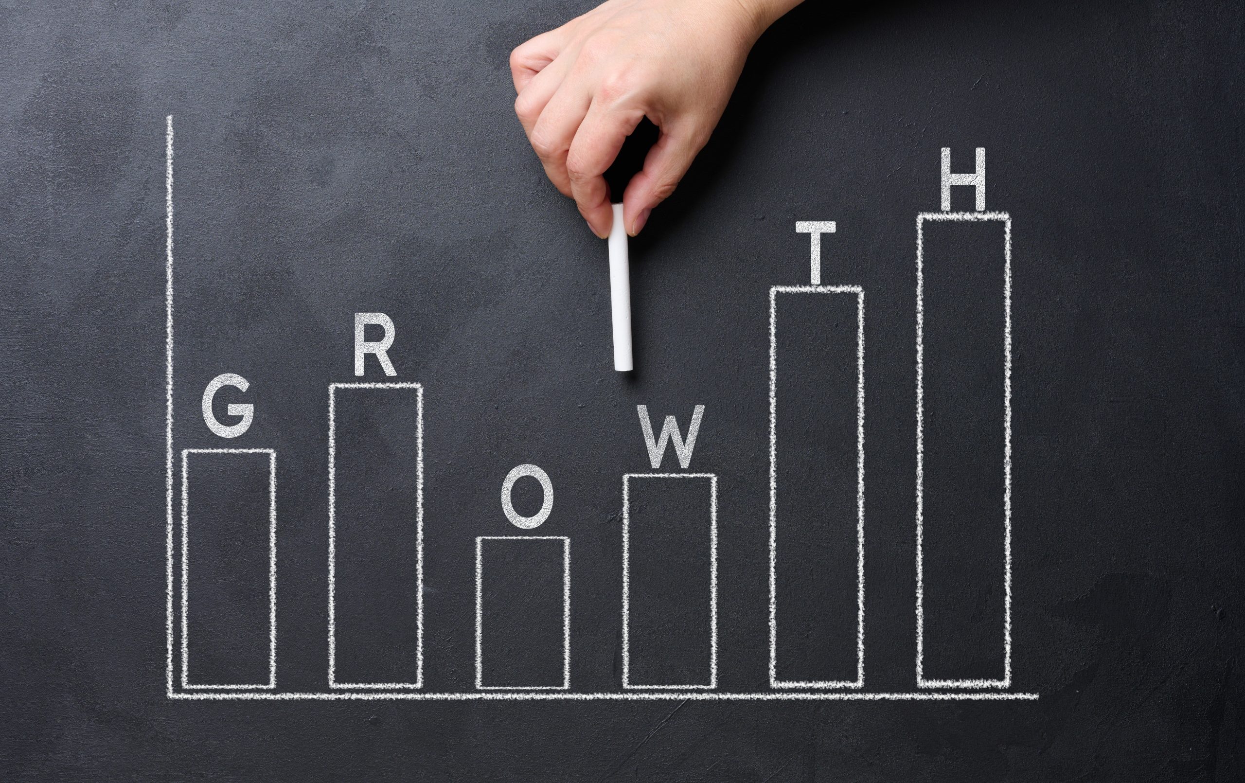 A woman's hand points to a graph with growing indicators drawn o
