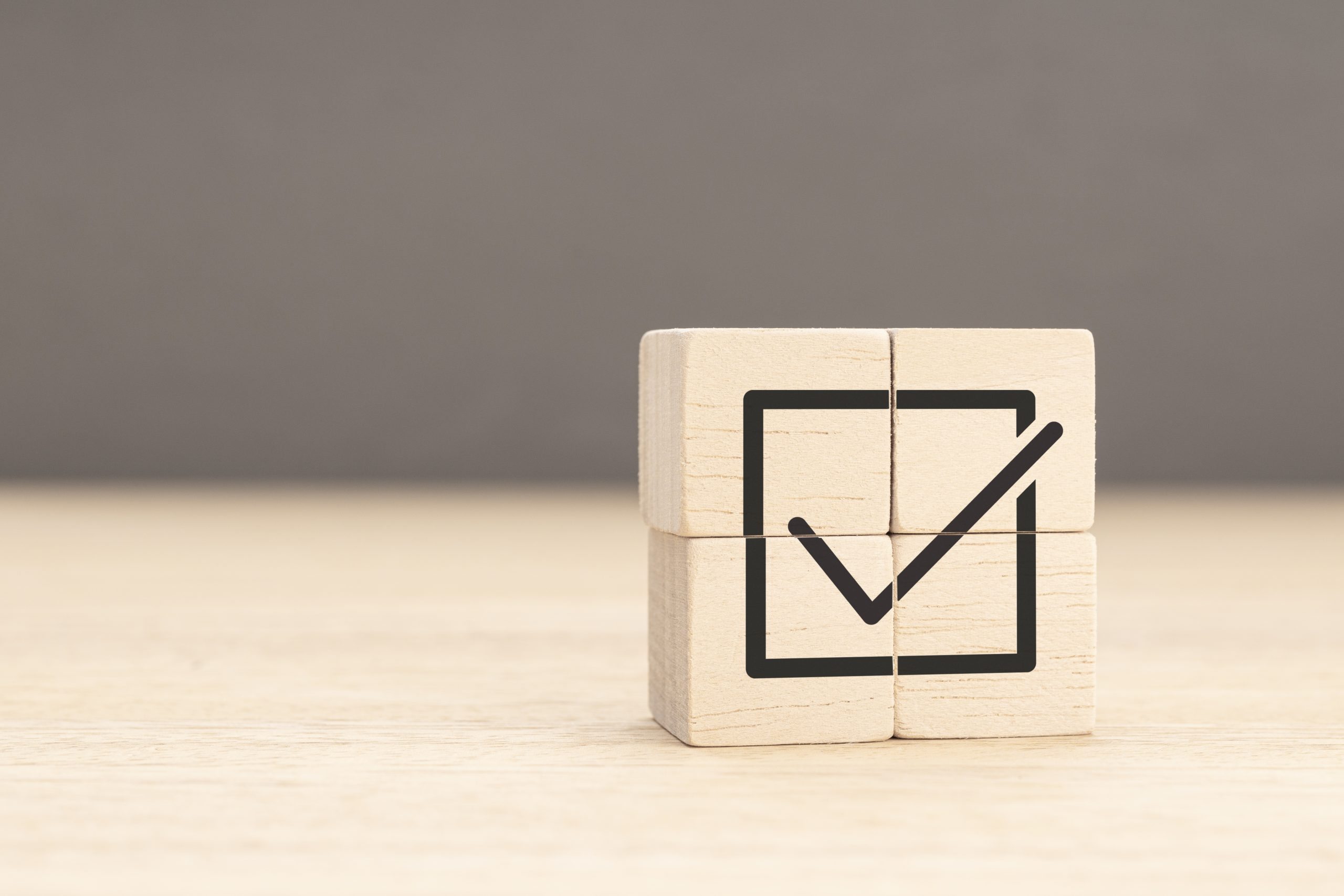Corporate regulatory and compliance. Goals achievement and business success. Task completion. Wooden cube with checkmark icon. Copy space